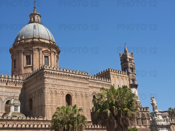 Historic cathedral with large dome and small town character, surrounded by palm trees, under a blue
