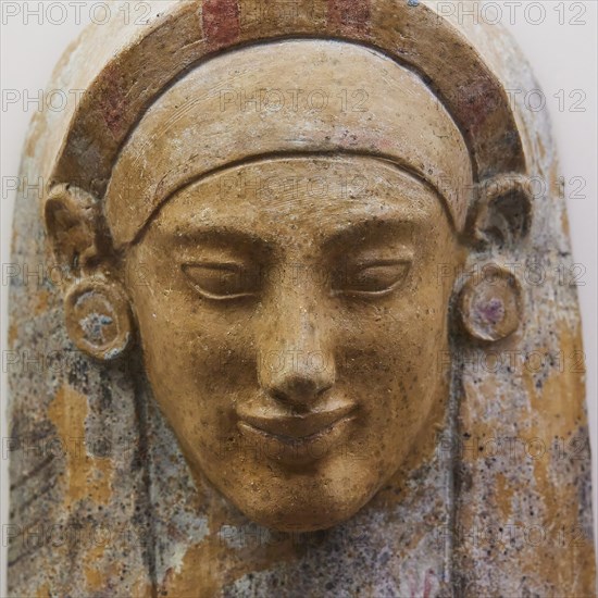 Female terracotta bust, A coloured stone relief of an ancient face with detailed facial features,