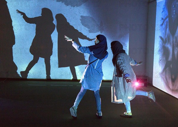 Two woman look at an exhibition by the German artist Otto Piene in Tehran on 6 April 2015 and make