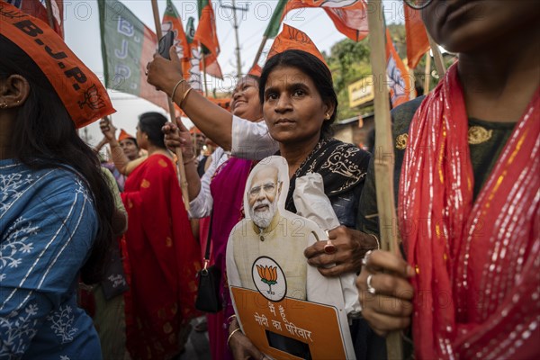 Bharatiya Janata Party (BJP) supporters holds a cutout of Narendra Modi as they arrives to to see a