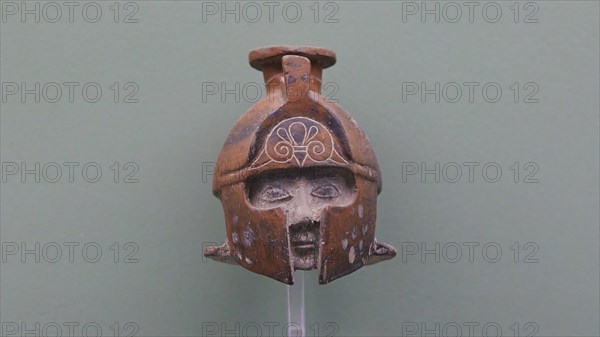 Aryballos, Ceramic vessel, Ancient sculpture of a helmet with a human face in front, brown against
