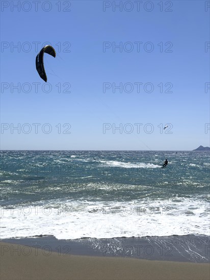 Kitesurfer kite surfer surfing in strong wind and waves rough sea choppy sea with inflated sail,