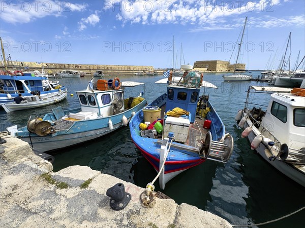Several small fishing boats in historic Venetian harbour of Heraklion, left in the background