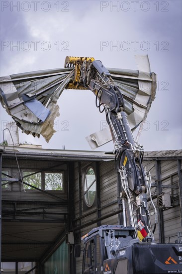 An excavator tears off the roof of a building, debris falls down, demolition, Saarbruecken,