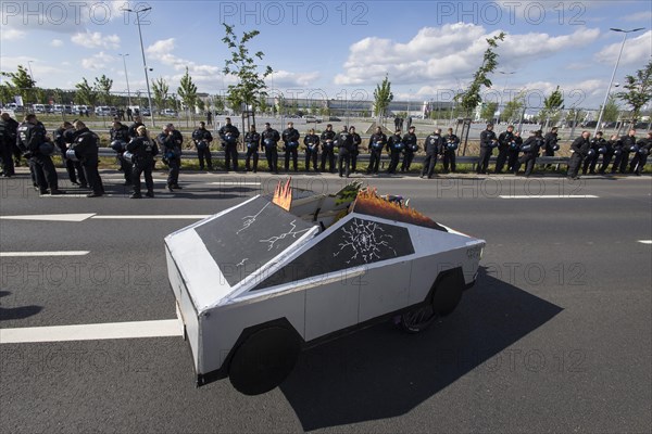 A Cybertruck cardboard model in front of the factory premises guarded by police officers during the