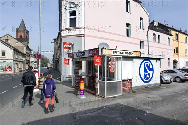 A pedestrian walks past a kiosk in Gelsenkirchen with a large S04 logo of FC Schalke 04 on it,