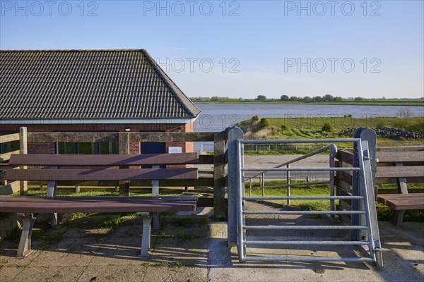 Self-closing door and bench on the dyke crest near Tetenbuell, Nordfriesland district,