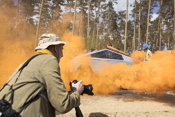A Tesla Cybertruck made of cardboard between the smoke of an orange fog pot during the