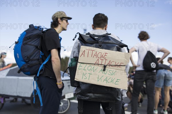 Participants with cardboard sign Attack, attack, Elon Musk is poop at the demonstration Water.