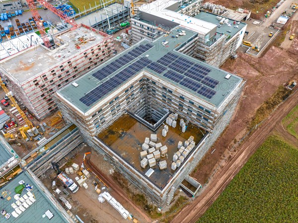 Construction site with buildings in shell construction and installed solar panels, stored building