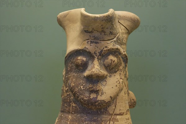 Large antique sculpture of a face with faded colours against a green background, interiors,