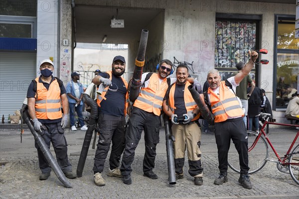 Employees of a cleaning service pose with their leaf blowers for a photo after the street parade of