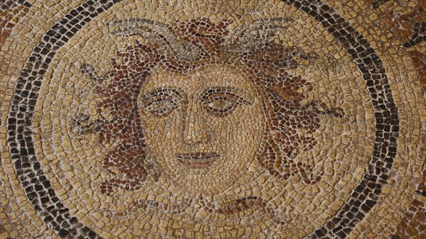 Detailed and artistic antique mosaic of a female face surrounded by plants, head of Medusa,