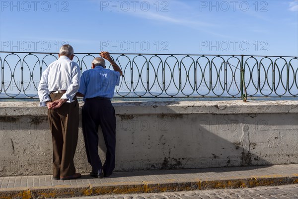 Senior citizen looking over a parapet on the street, Vejer, Andalusia, Spain, Europe