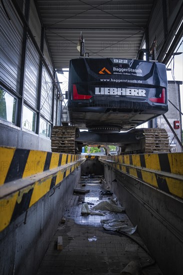 An excavator stands on a lifting platform inside a building, demolition, Saarbruecken, Germany,