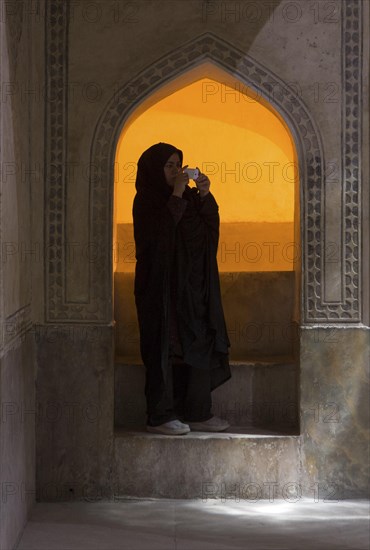 An Iranian woman in traditional dress with a chador photographed with a digital camera at the