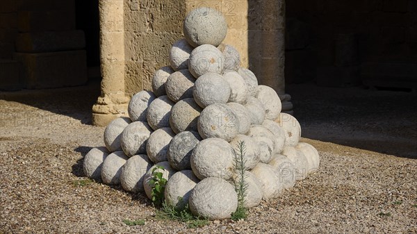 Large pyramid of stone cannonballs on a gravel floor, outdoor area, Archaeological Museum, Old