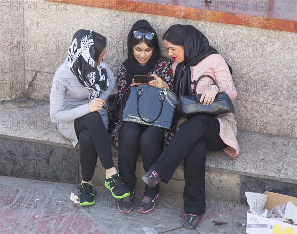 Three young Iranian woman look at a smart phone in Tehran on 07/04/2015, Tehran, Iran, Asia