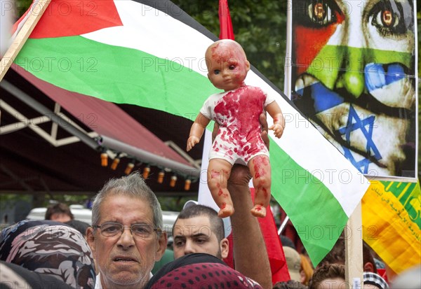 A Palestinian holds a doll coloured with red paint during the Al Quds demonstration in Berlin. Over