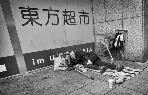 Homeless, Berber, sleeping, lying on pavement, Bible, shopping trolley, belongings, bag, Chinese