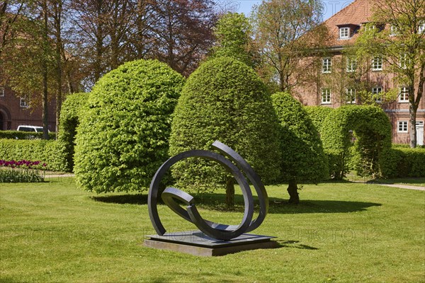 Art object and european hornbeams (Carpinus betulus) with topiary in the Marktstrasse park in