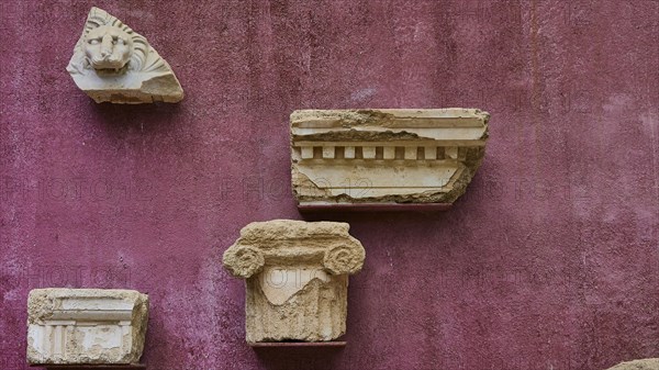 Architectural fragments of stone, ancient marble pieces attached to a wall, outdoor area,