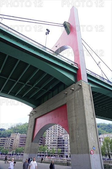 La Salve Bridge, A large bridge with red and green elements towering over buildings and