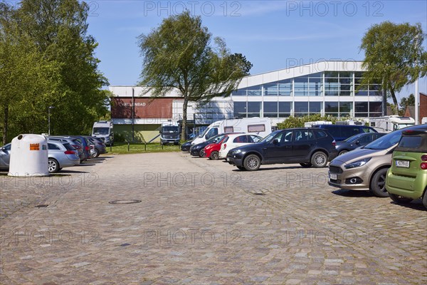 Used glass container, car park and indoor swimming pool in Niebuell, Nordfriesland district,