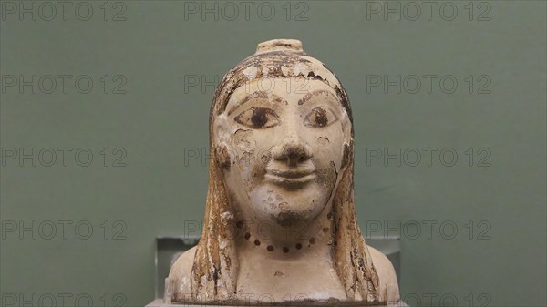 Aryballos, ceramic vessel, ancient bust of a face against a green background, partially damaged,
