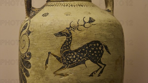 Antique jug with a detailed image of a stag and floral ornaments in black on a beige background,
