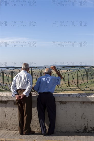 Senior citizen looking over a parapet on the street, Vejer, Andalusia, Spain, Europe