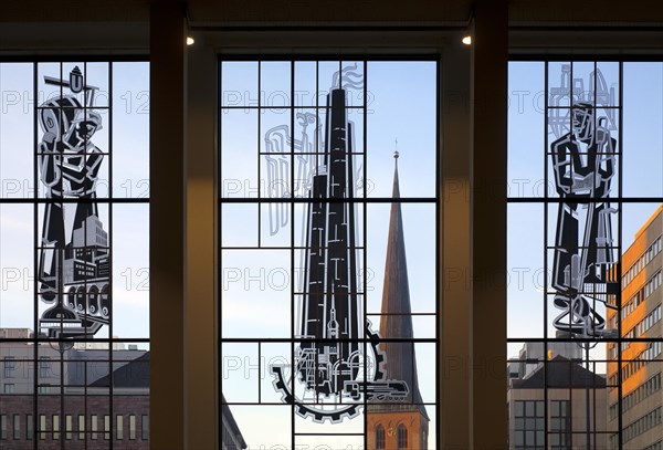 View through the glass front of the main railway station with three pictorial stained glass windows