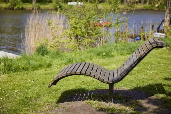 Public wooden deckchair on the banks of the Westersielzug in Friedrichstadt, North Friesland