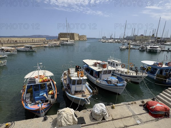Several small fishing boats in historic Venetian harbour of Heraklion, left in the background