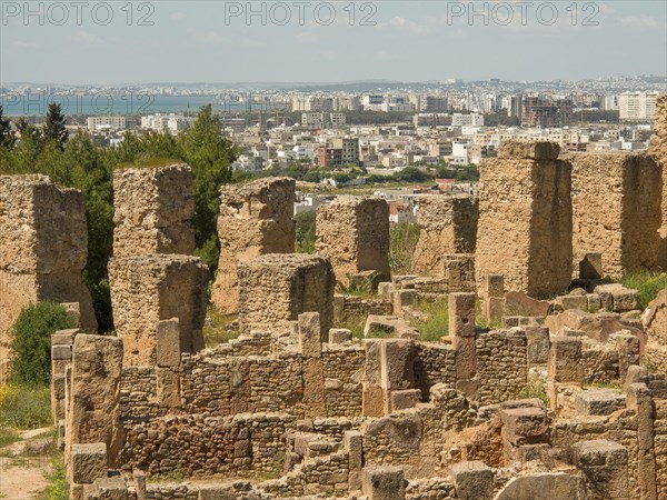 Historic stone ruins with a view of the modern city in the background, sweeping views under a blue