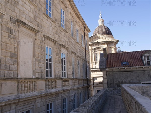 Old buildings with stone walls and many windows, in the background a dome under a blue sky, the old