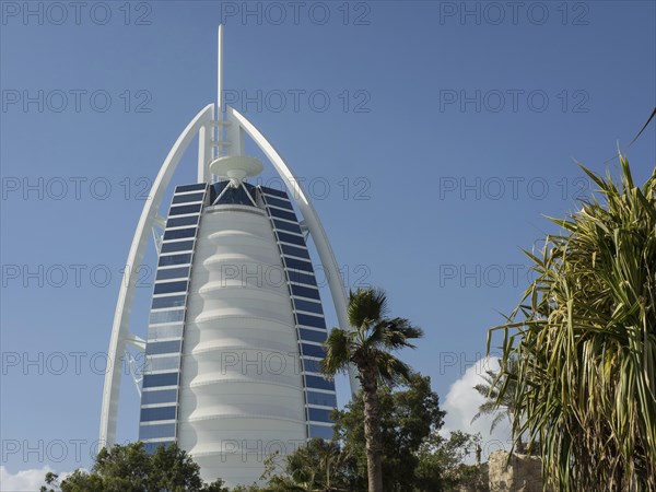 The Burj Al Arab Hotel in Dubai with palm trees and green spaces in the foreground, dubai, arab
