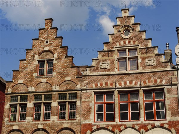 Brick architecture with magnificent stepped gables and windows silhouetted against a blue sky,