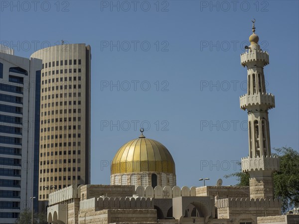 Islamic mosque with golden dome and minaret in front of modern skyscrapers, Abu Dhabi, United Arab