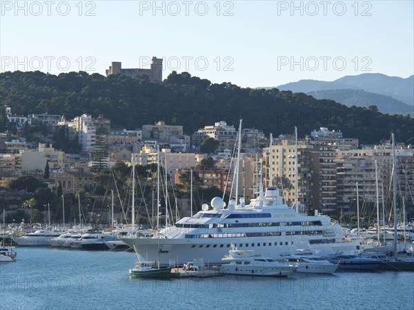 City by the sea with a harbour full of yachts and boats, surrounded by mountains under a clear sky,