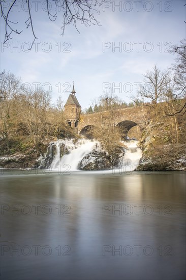 Beautiful landscape in winter with ice and snow. Waterfall of the river Elz near the castle