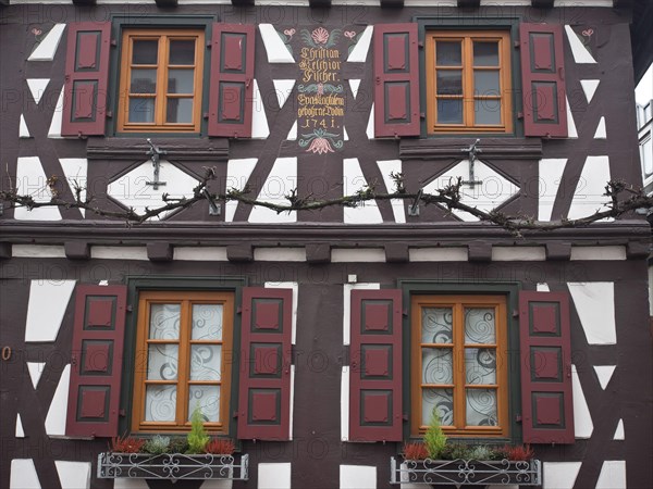 Detail of a half-timbered house with red shutters and decorative flowers on the window, kandel,