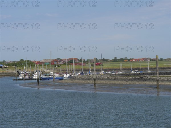 A village harbour with several boats moored, surrounded by the coastal landscape, Baltrum Germany