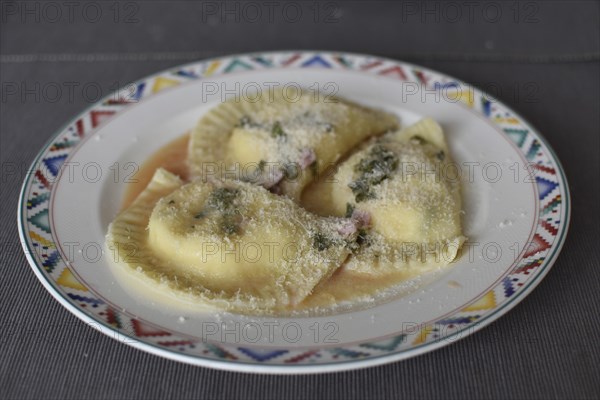 Preparation of fresh homemade pasta mezzaluna with ricotta, garlic wine sauce and parmesan cheese