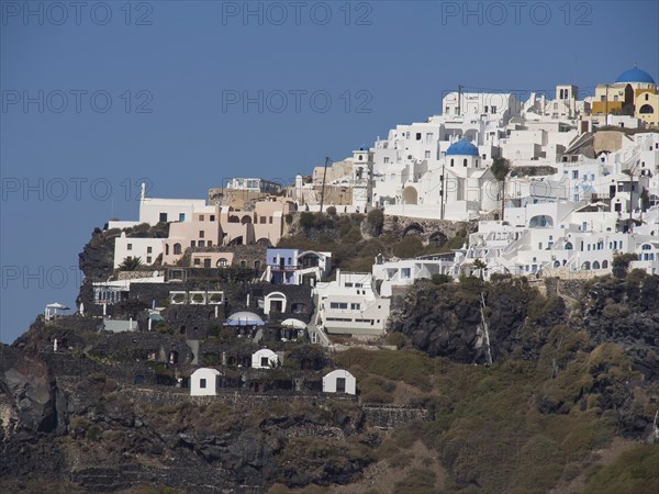 View of white buildings with blue domes on a cliff under a clear blue sky, The volcanic island of