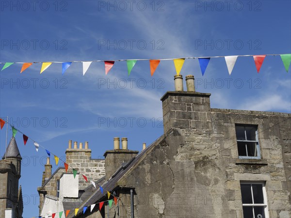 Old village houses with colourful pennants on a sunny day with a bright blue sky, grey houses with