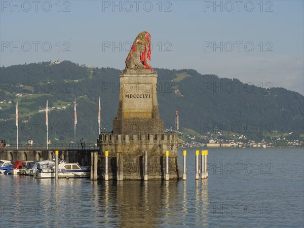 Stone sculpture of a lion at the harbour with surrounding boats and mountain view, towers at a