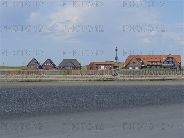 Coastal landscape with several houses along the beach and sea, under blue sky, Baltrum Germany