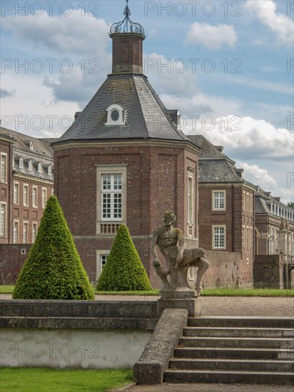 Historic castle with stone statue and steps, surrounded by trees, historic castle with a green park