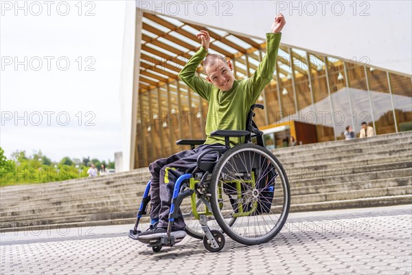 Disabled man in wheelchair celebrating raising arms proud to be in the university